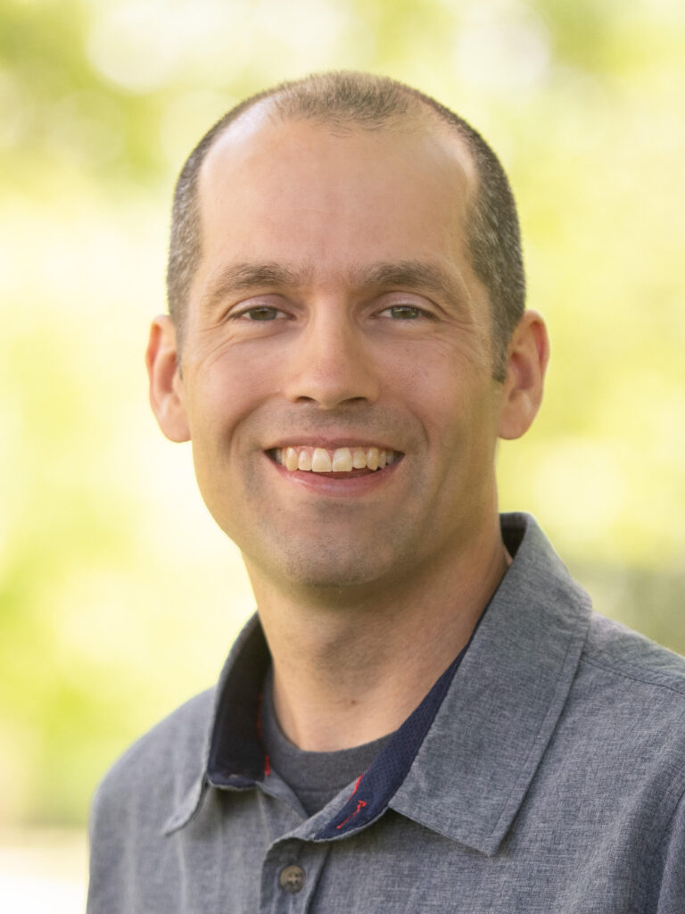 Russell Adrian headshot, with outdoor background