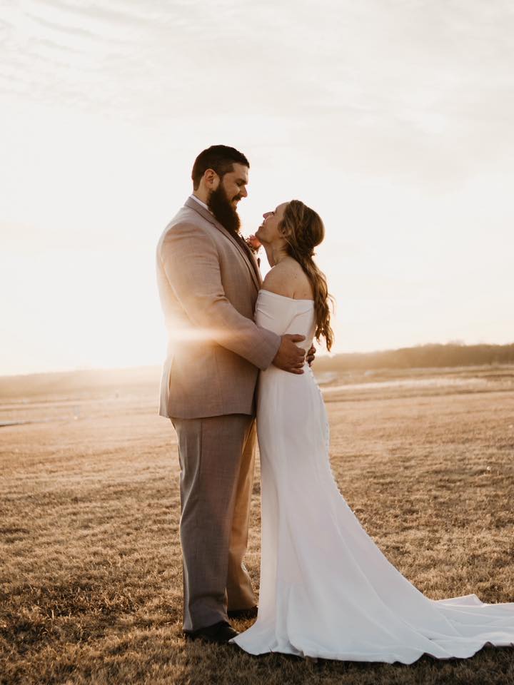 Wedding photo of Kyle Wilson & Katelyn Fatten, outdoors with sun setting behind them