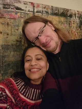 Angela Muhuri in dark red sweater with yellow stripes & Steve Unruh in dark-colored shirt