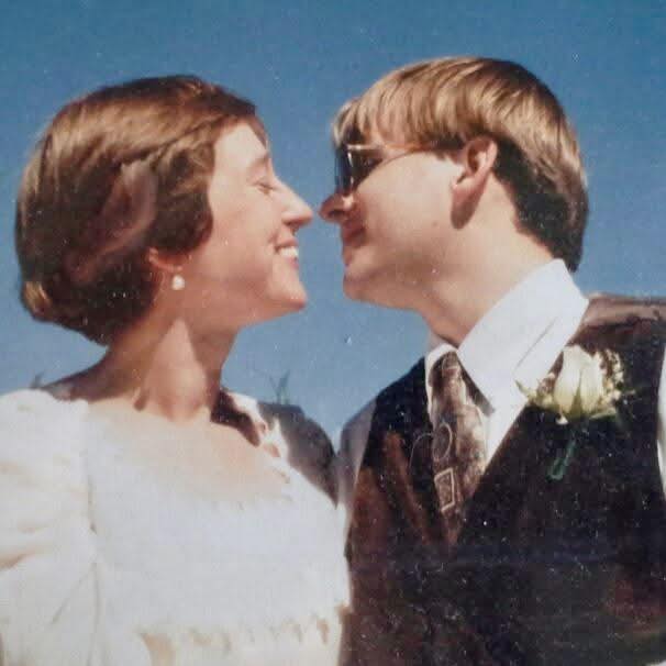 Wedding photo of Bev Baumgartner & Joel Ewy, outside with blue sky behind their heads