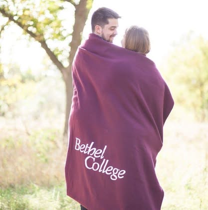 Josh Booth & Mattison Hiebner wrapped in a maroon Bethel College blanket
