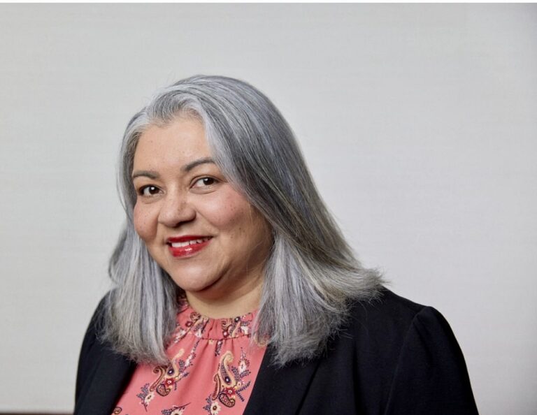 Headshot of Karen Gonzalez in salmon-colored embroidered blouse and black sweater