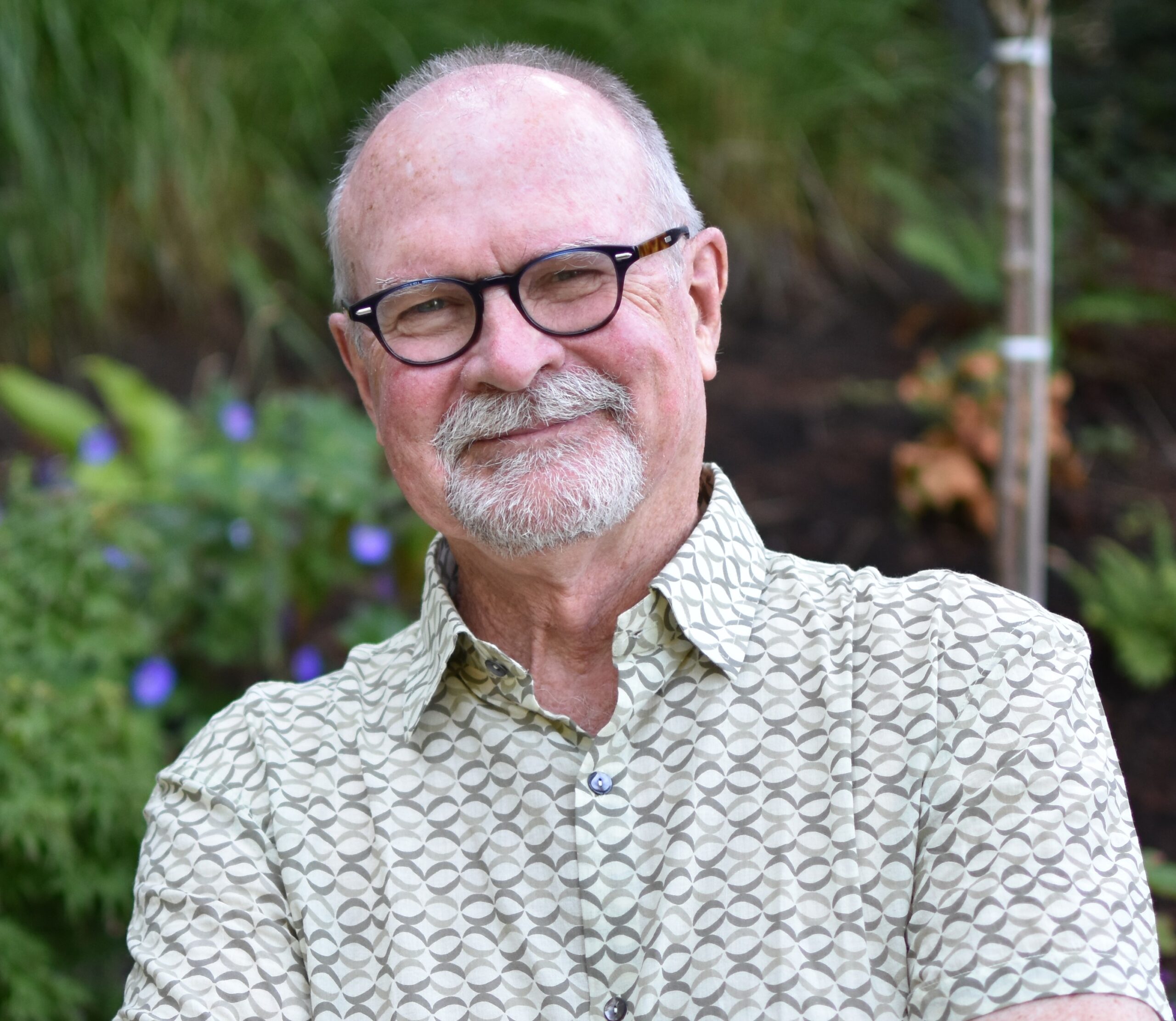 White man with glasses and short gray beard in a light-colored print collared shirt